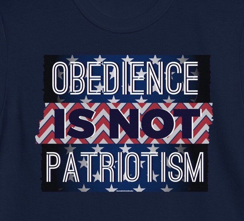 May include: Navy blue t-shirt with the white text "OBEDIENCE IS NOT PATRIOTISM", set against a backdrop of the American flag. The design has a distressed, vintage appearance.