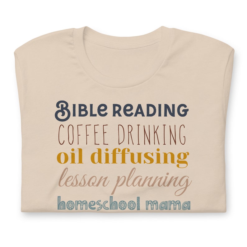 May include: Beige t-shirt with the text "Bible Reading, Coffee Drinking, Oil Diffusing, Lesson Planning, Homeschool Mama" in various colours.