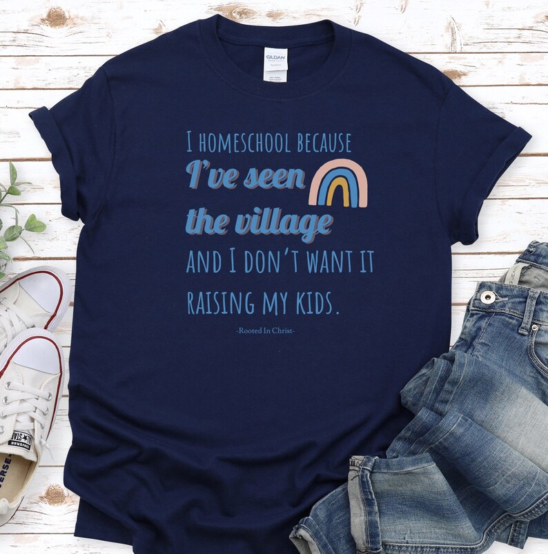 May include: Navy blue t-shirt with a rainbow graphic and the text "I homeschool because I've seen the village and I don't want it raising my kids. -Rooted In Christ- "