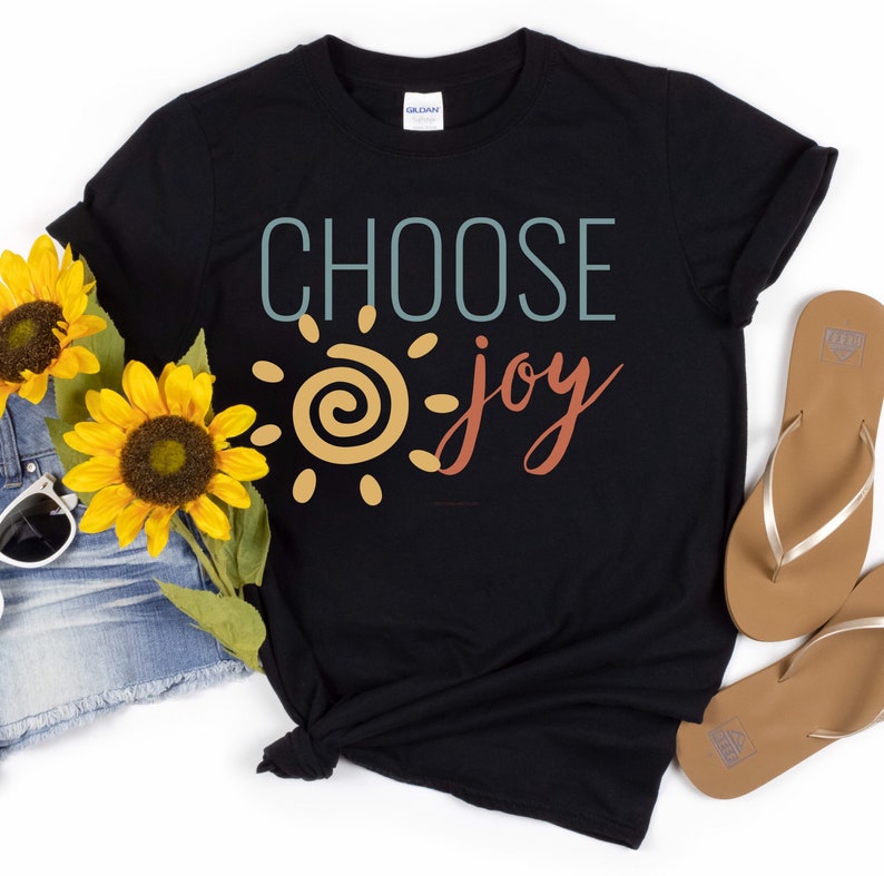 May include: Black t-shirt featuring a graphic design of a sun with a swirl inside and the text "CHOOSE joy" in a colourful retro font.