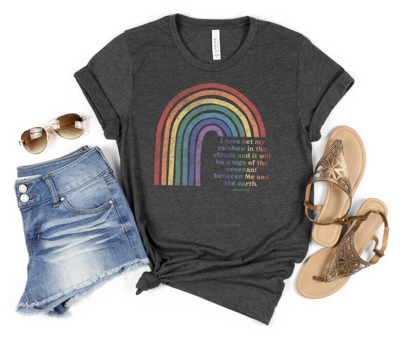 Pu&ograve; includere: Una maglietta grigio scuro melange con un motivo arcobaleno e il testo "Ho posto il mio arcobaleno nelle nuvole, e sar&agrave; segno dell'alleanza tra me e la terra." Genesi 9:13