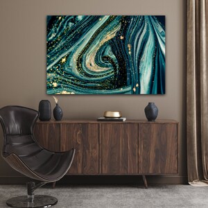 Puede incluir: Impresi&oacute;n de arte abstracto con pintura azul y verde en espiral con detalles de purpurina dorada. La impresi&oacute;n est&aacute; enmarcada y colgada en una pared sobre un armario de madera.