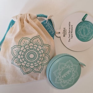 Può includere: Nastro di misura retrattile color turchese con un design a mandala, confezionato in una borsa con coulisse con un design a mandala turchese. La borsa e il nastro di misura sono etichettati con "Knitter's Pride" e "The Mindful Collection".