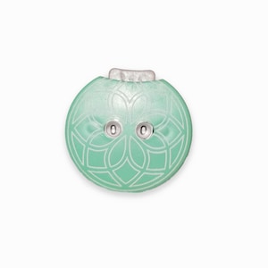 以下が含まれることがあります： 銀色の金属製のリングと、それぞれに「0」の数字が書かれた銀色の金属製の円が2つ付いた、丸いターコイズブルーのボタン。ボタンには、白い複雑なデザインが施されています。