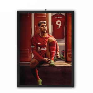 May include: A soccer player wearing a red jersey with the number 9 and the name "FIRMINO" on the back sits in a locker room tying his shoe laces. The locker room has red lockers with metal grates.