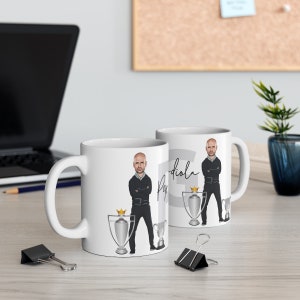 May include: Two white ceramic mugs with a cartoon image of a man in a black suit and a trophy. The text "Pep Guardiola" is written on the mug.