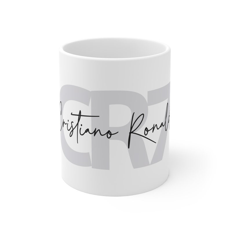 May include: White ceramic mug with the letters "CR7" in gray and the text "Cristiano Ronaldo" in black cursive.