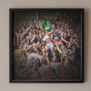 Puede incluir: Impresión enmarcada que representa una multitud jubilosa. Una persona es alzada por la multitud, rodeada de individuos que vitorean. Se ve una bandera verde y amarilla. El marco es de color marrón oscuro.