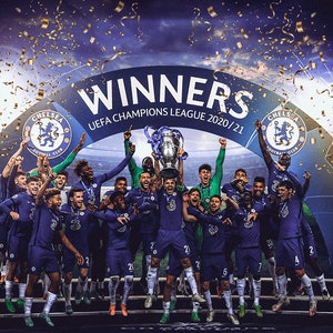 May include: Chelsea football team celebrating their UEFA Champions League victory in 2020/21. Players in blue uniforms hold the trophy aloft, confetti and fireworks in the background. The word "WINNERS" is displayed above the team.