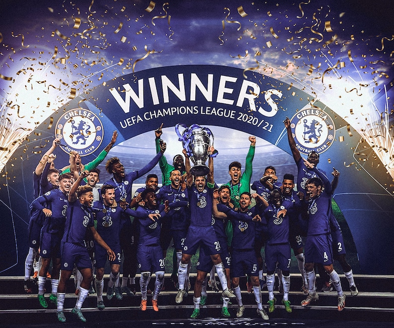May include: Chelsea football team celebrating their UEFA Champions League victory in 2020/21. Players in blue uniforms hold the trophy aloft, confetti and fireworks in the background. The word "WINNERS" is displayed above the team.