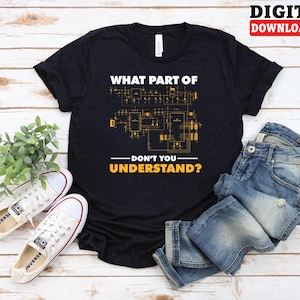 May include: Black t-shirt with the text "WHAT PART OF DON'T YOU UNDERSTAND?" in white and yellow. The shirt features a circuit board design. The image also shows white sneakers, blue jeans, and a plant on a wooden surface.