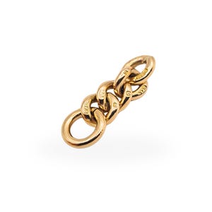 May include: A close-up of a gold-colored chain link with three interconnected oval links and a circular ring. The chain links have the markings "1873" and "375". The jewelry is set against a white background.