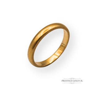 May include: A gold-colored ring with a smooth, rounded band. The ring is set against a white background, with the text "PRESTIGE GOLD UK" at the bottom. The ring appears to be made of solid gold.