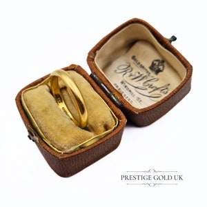 May include: A gold wedding band in a brown velvet ring box. The box is inscribed with "Goldsmiths R. & W. Crafts Windmill St.  Bradford."