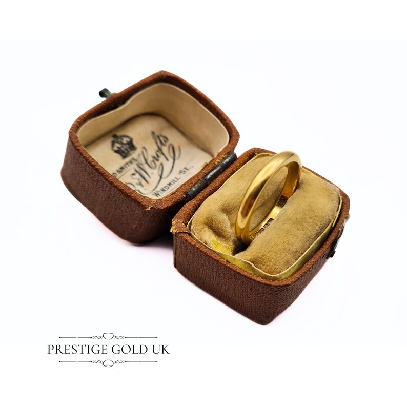 May include: A gold wedding band in a brown velvet ring box. The box is labeled "Smiths Jewellers Windmill St."