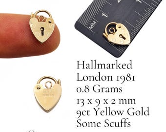 May include: A heart-shaped, gold-colored padlock with a keyhole and a small loop. The padlock is 0.5 inches long, 0.35 inches wide, and 0.08 inches thick. The text "Hallmarked London 1981" is visible.