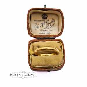 May include: A gold wedding band in a brown velvet ring box. The box is inscribed with "Goldsmiths R & W Crofts Windmill St. Gravesend."