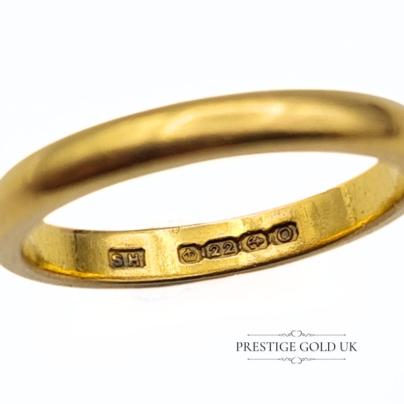 May include: A gold wedding band with a hallmark that reads "22ct" and "SH".