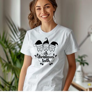 May include: White t-shirt featuring a graphic of three smiling teeth wearing Santa hats, with the text "oh christmas teeth" in a festive design. A fun and unique holiday-themed apparel item.