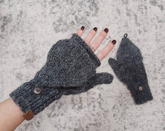 May include: A pair of gray knitted fingerless gloves with a button detail. One glove is a mitten style with a thumb hole, while the other is a fingerless glove with a fold-over cuff.