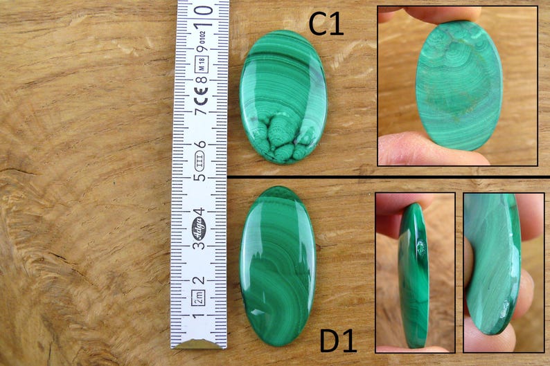 May include: Two oval-shaped malachite gemstones with a ruler for scale. The gemstones are a vibrant green with swirling patterns. One is labeled "C1" and the other "D1". The ruler shows measurements in inches.