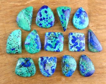 May include: A collection of thirteen polished azurite-malachite cabochons in various shapes, including teardrops, triangles, and rectangles. Each stone displays a vibrant mix of deep royal blue and bright turquoise green with unique patterns.
