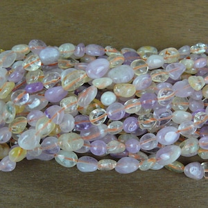 May include: A strand of mixed gemstone beads, featuring a mix of light purple, clear, and yellow beads. The beads are smooth and oval-shaped.