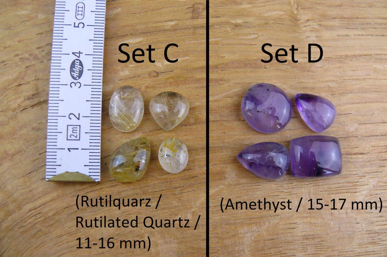 May include: Two sets of gemstone cabochons. Set C features four rutilated quartz cabochons in shades of yellow and gold, measuring 11-16 mm. Set D features four amethyst cabochons in shades of purple, measuring 15-17 mm.