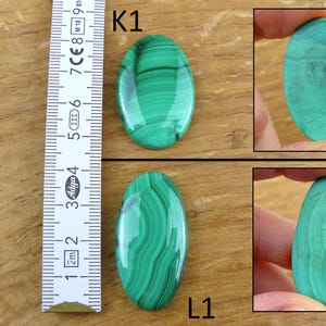 May include: Two oval-shaped malachite gemstones with a vibrant green color and distinctive banded patterns. One gemstone is shown next to a ruler, and two others are held by a person. The gemstones are approximately 2 inches in length.