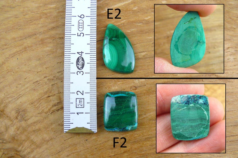 May include: Image of malachite gemstones with a ruler for scale. The gemstones are various shapes, including a teardrop and a rectangle. The malachite is a vibrant green color with swirling patterns. The ruler shows measurements in inches.