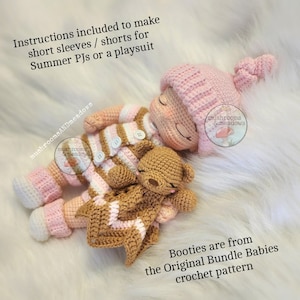 May include: A crocheted baby doll wearing a pink and white striped outfit, a pink hat, and pink booties. The doll is holding a brown crocheted teddy bear. The doll is lying on a white fluffy surface. Instructions included to make short sleeves/shorts for Summer PJs or a playsuit. Booties are from the Original Bundle Babies crochet pattern.