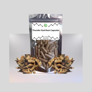 Puede incluir: Una bolsa transparente y resellable llena de cápsulas marrones etiquetadas como "Thunder God Root Capsules". La bolsa está centrada, con trozos de raíz seca a ambos lados. La etiqueta también indica "Suplemento dietético" y "Todo natural - NON-GMO - VEGAN - Sin rellenos."
