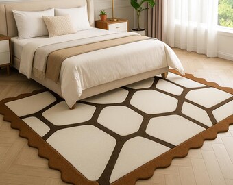 May include: A rectangular area rug with a geometric pattern in shades of brown and cream. The rug features a repeating pattern of interconnected shapes, with a scalloped border. The rug is placed in a bedroom setting, under a bed.