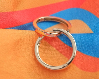 May include: Two silver hoop earrings on a colorful striped fabric background.