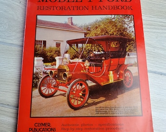 Könnte beinhalten: Ein rotes Handbuch zur Restaurierung eines Ford Model T mit einem Foto eines roten Ford Model T aus dem Jahr 1909 auf dem Cover. Das Buch trägt den Titel "Model T Ford Restoration Handbook" und enthält den Text "Authentic photos - specifications Step-by-step restoration procedure" unter dem Foto. Herausgegeben von Clymer Publications.