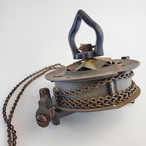 May include: Antique brass and black metal chain pull with a decorative chain. The chain is wrapped around a spool and the pull has a decorative handle.