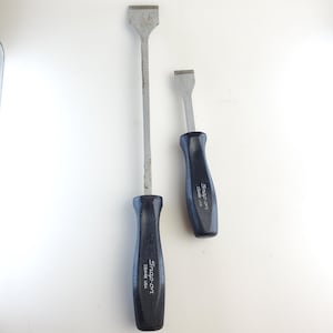 May include: Two Snap-on brand metal putty knives with black rubber handles. The larger knife is approximately 12 inches long and the smaller knife is approximately 6 inches long.