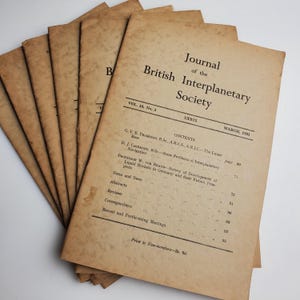 May include: A stack of vintage journals from the British Interplanetary Society, dated March 1951. The covers are a faded tan color with black text, including the journal's title, volume number, and table of contents. The pages show signs of age.