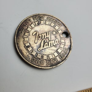 May include: A round, gold-colored metal token with the text "Quality Boot Making Over Sixty Years" and the logo "Tony Lama" with a star.