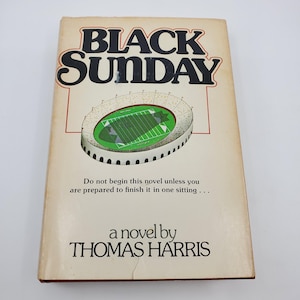 May include: A well-worn paperback book with the title "BLACK SUNDAY" by Thomas Harris. The cover shows a stadium illustration and the text: "Do not begin this novel unless you are prepared to finish it in one sitting..."