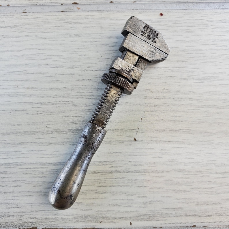 Puede incluir: Una llave inglesa de plata con mango de madera. La llave est&aacute; etiquetada con "GEM T.M."