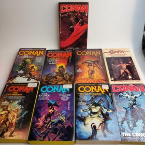 May include: A collection of ten paperback books with colorful covers featuring illustrations of Conan the Barbarian. The books are titled "Conan the Magnificent", "Conan the Valorous", "Conan the Destroyer", "Conan the Triumphant", "Conan the Raider", "Conan the Victorious", and "Conan the Conqueror".