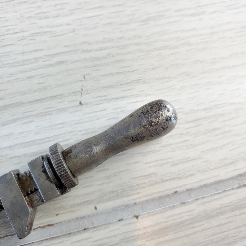 Puede incluir: Una llave inglesa de plata con un mango desgastado. La llave es de metal y tiene un agarre texturizado.