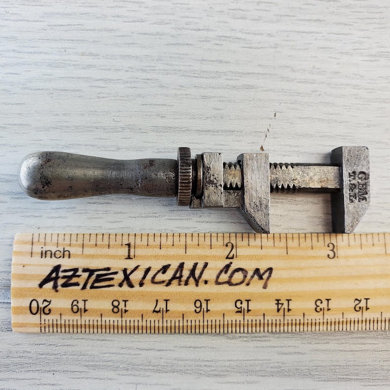 Puede incluir: Una llave inglesa de plata con mango de madera, que mide aproximadamente 7,6 cm de largo. La llave est&aacute; etiquetada como "GEM 3 1/2".