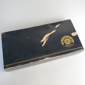 May include: A black box with a gold border and a gold logo that says "Taurus Brasil".