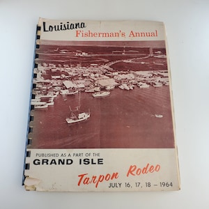 May include: A vintage Louisiana Fisherman's Annual booklet for the Grand Isle Tarpon Rodeo, held July 16-18, 1964. The cover features an aerial photograph of a harbor with numerous boats.