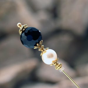 This classically styled hat pin features a deep jet black faceted glass coin bead above a cream premium faux glass pearl.  I accented with rich gold plated bead caps and spacer beads.