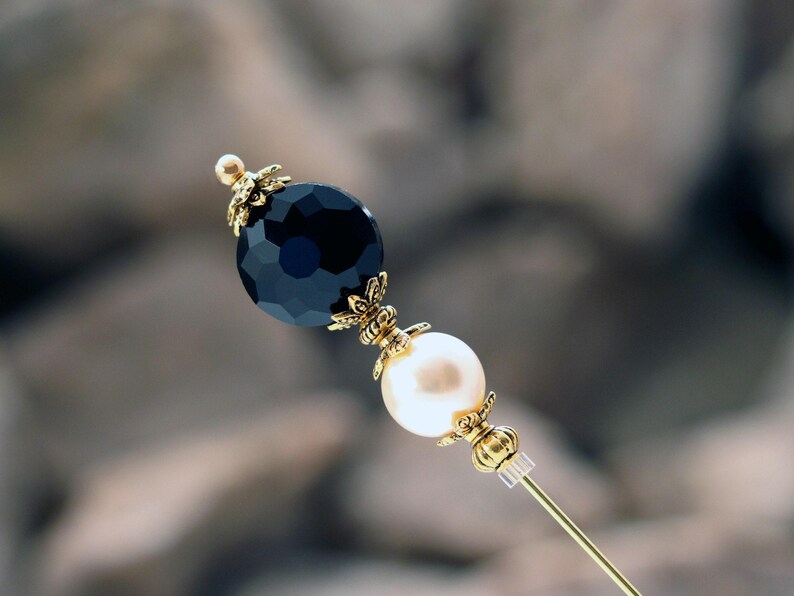 This classically styled hat pin features a deep jet black faceted glass coin bead above a cream premium faux glass pearl.  I accented with rich gold plated bead caps and spacer beads.
