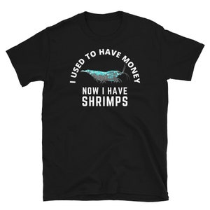 May include: Black t-shirt with white text that reads "I used to have money now I have shrimps". A blue shrimp is pictured above the text.