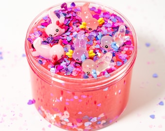 May include: A clear plastic jar filled with pink slime, pink and purple glitter, and small pink and clear plastic axolotl charms.